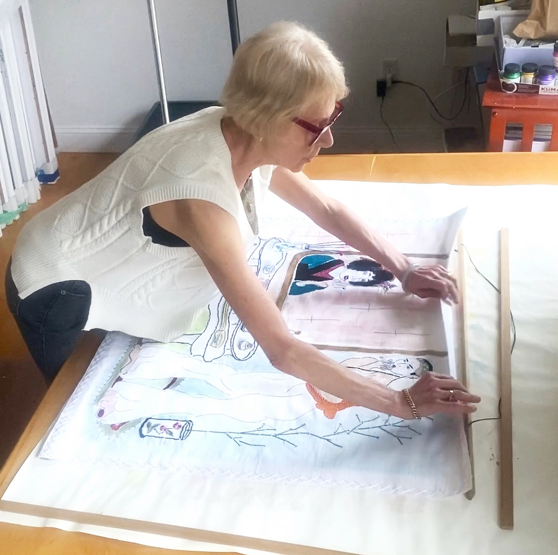 Carol Scavotto attaching a silk piece to it's frame.